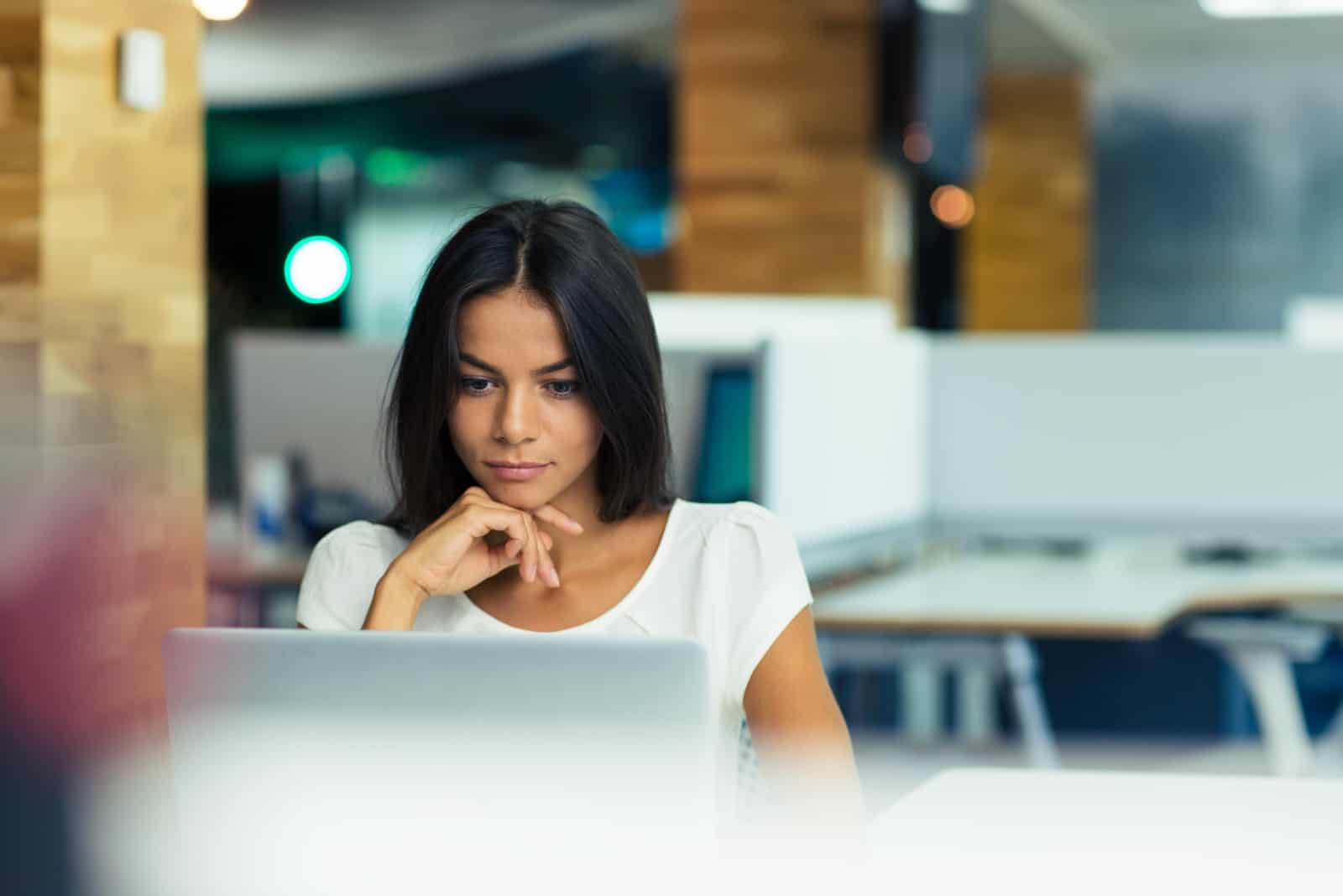 uma mulher de cabelo preto sentada atrás de um computador portátil