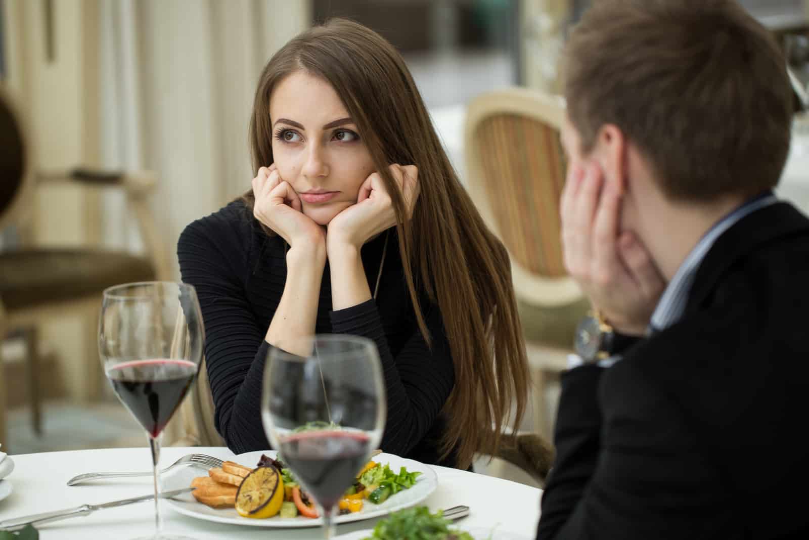 a confused woman sits at a table with a man