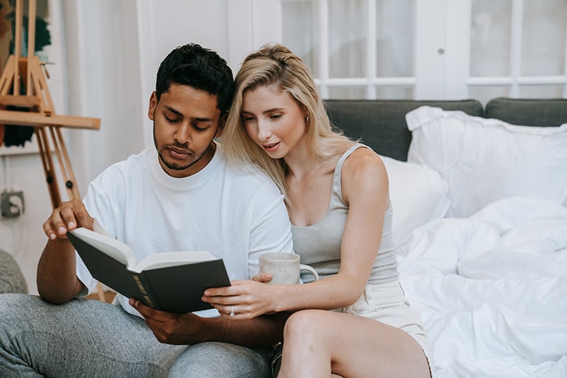 una coppia che legge un libro insieme a casa