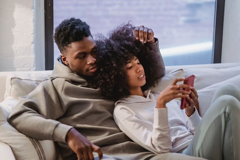 a couple relaxing on the couch looking at smartphone