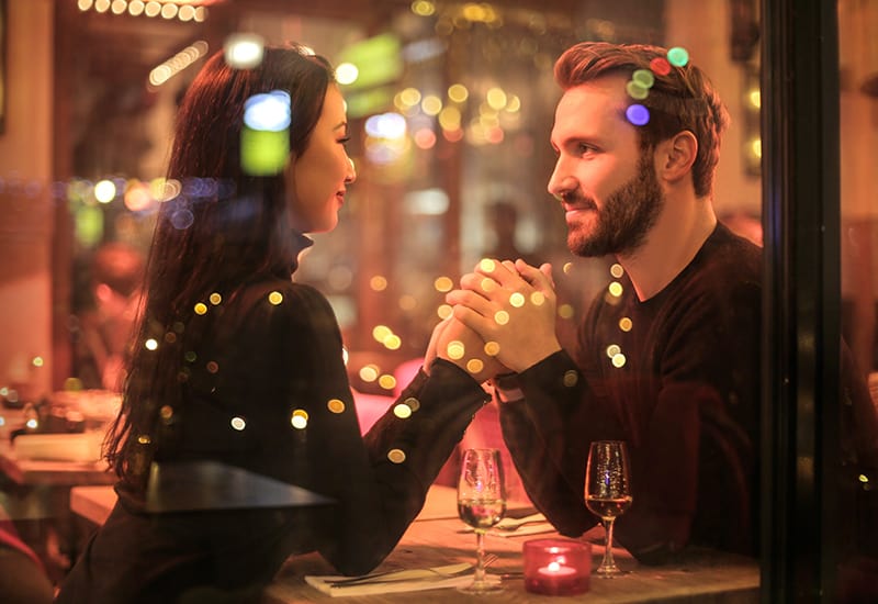 a loving couple holding hands sitting in romantic restaurant