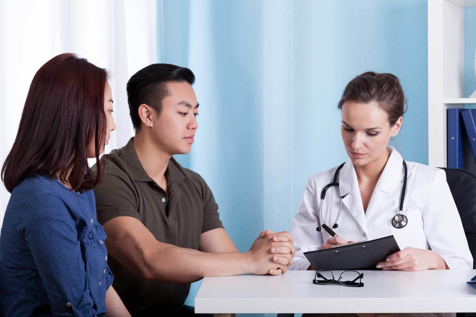 a man and a woman are sitting at a table with a doctor while they are talking
