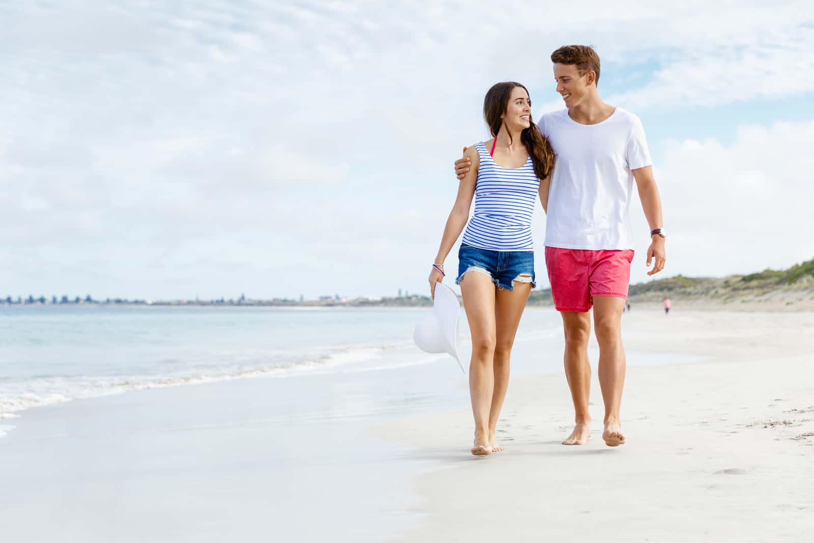 a man and a woman are walking along the beach and laughing