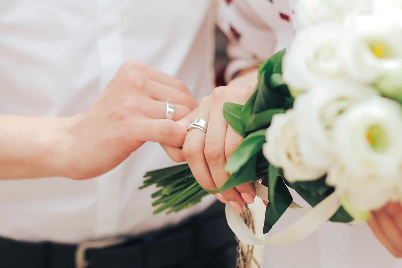 um homem e uma mulher estenderam as mãos com as alianças de casamento