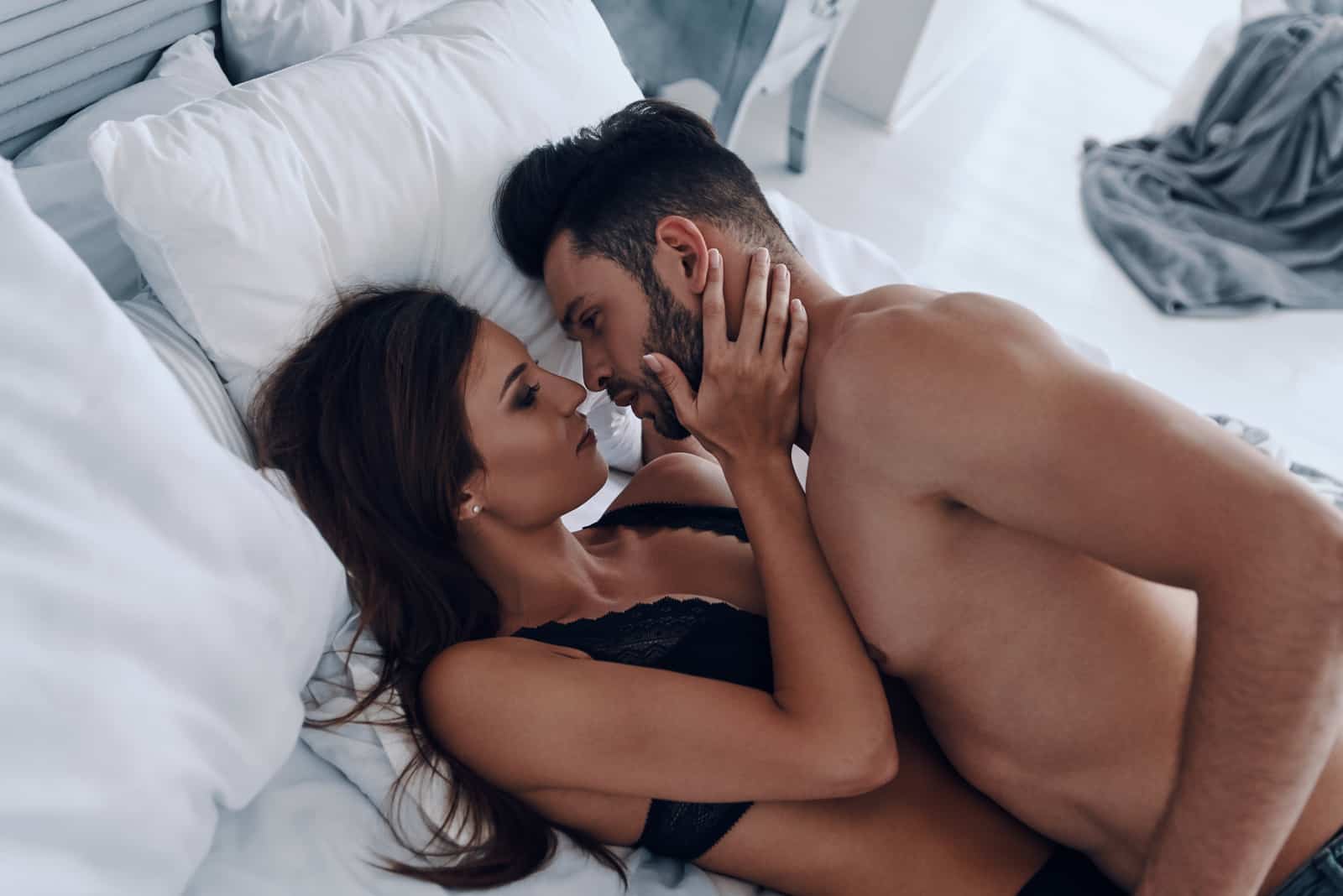 un hombre y una mujer besándose en la cama
