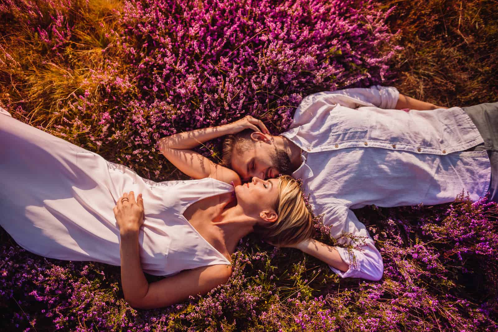 a man and a woman lie in a field embracing