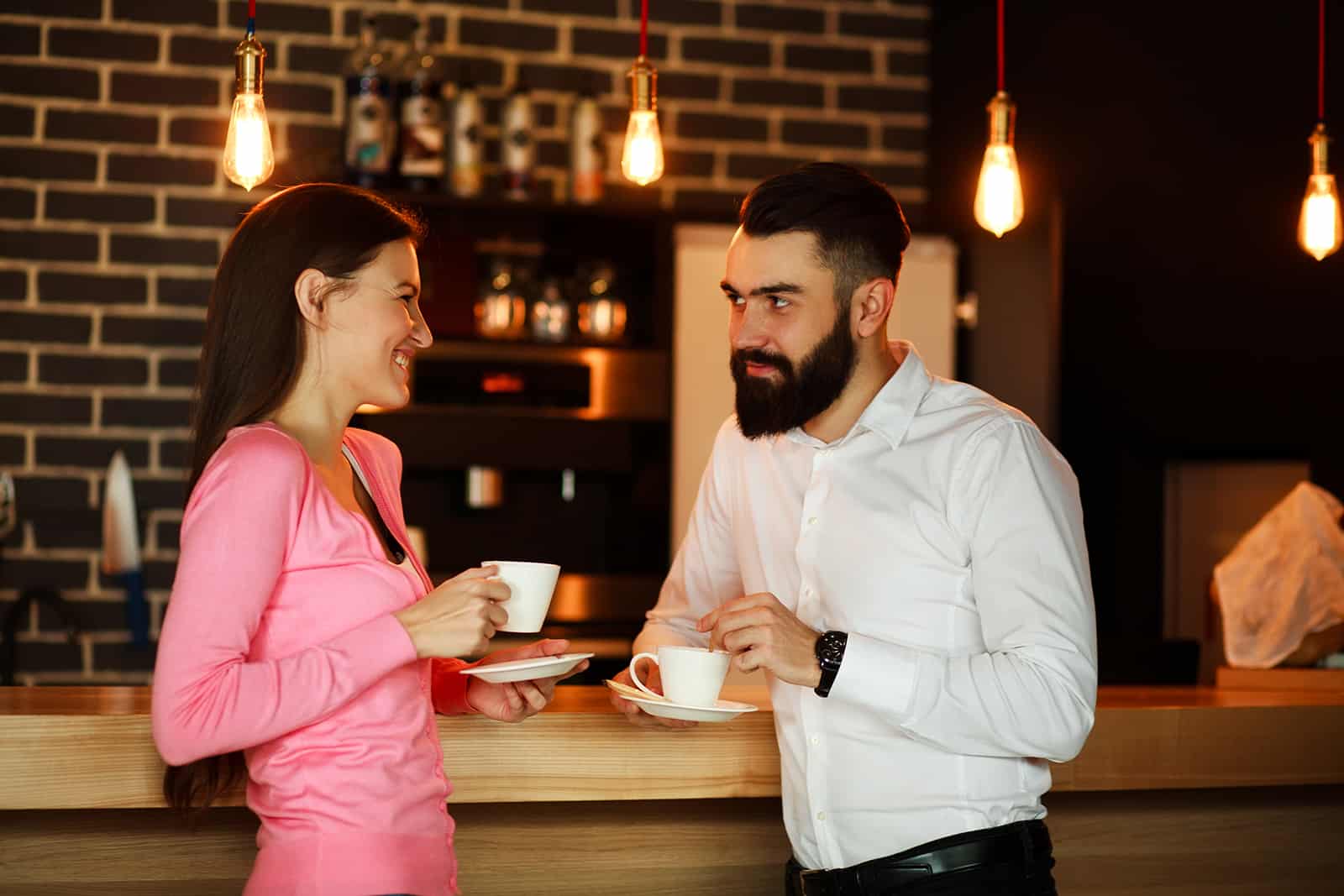a man and a woman looking at each other while having coffee together