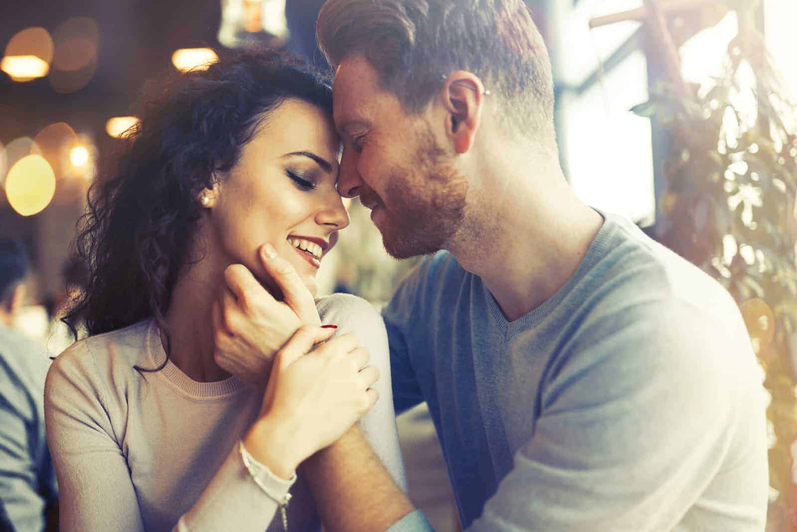 a man and a woman sit at a table and cuddle