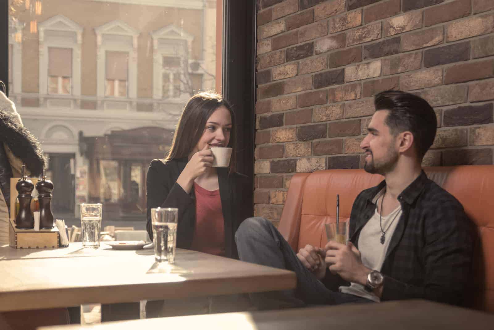 un hombre y una mujer se sientan en un café y hablan