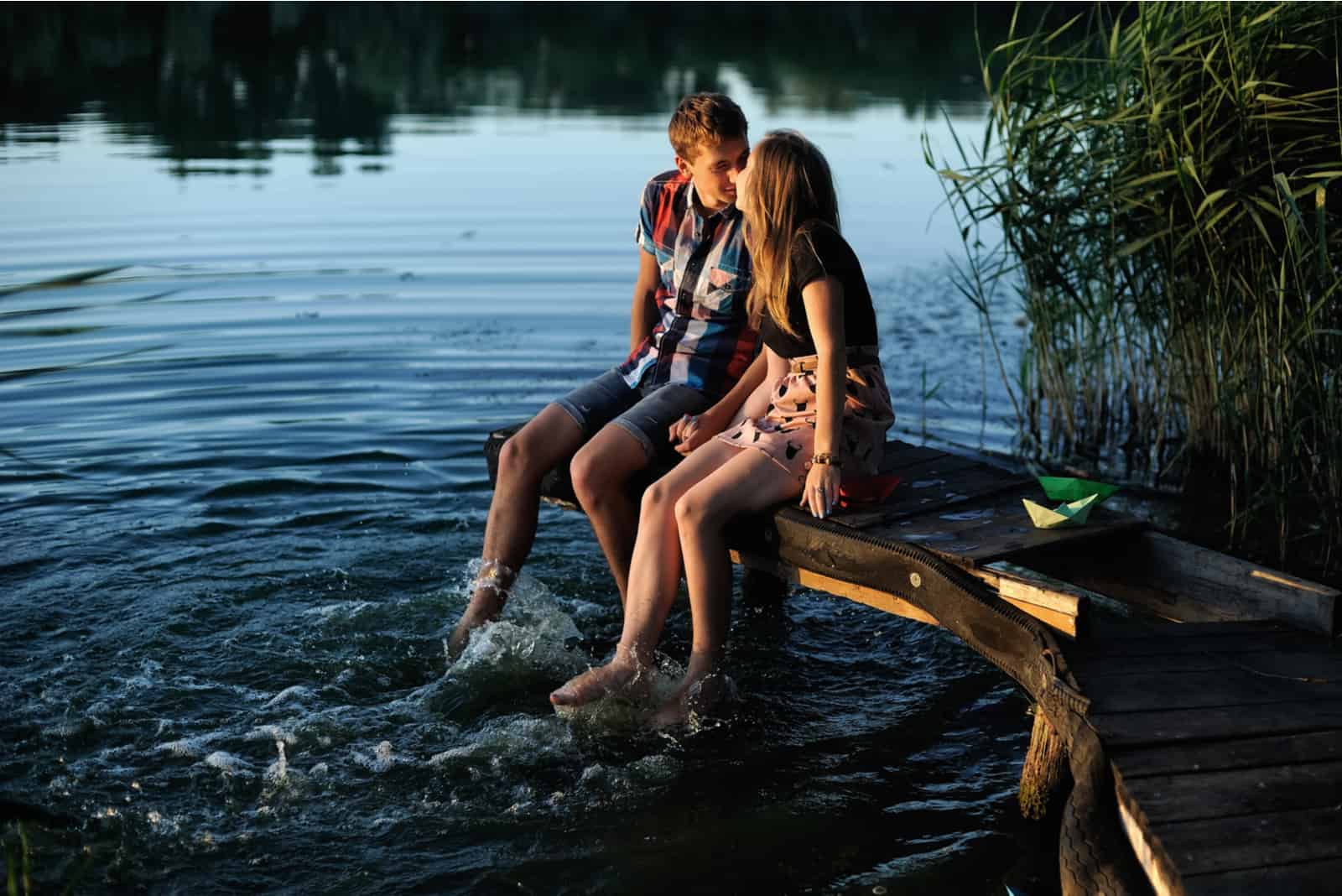 un uomo e una donna siedono sul molo e si baciano