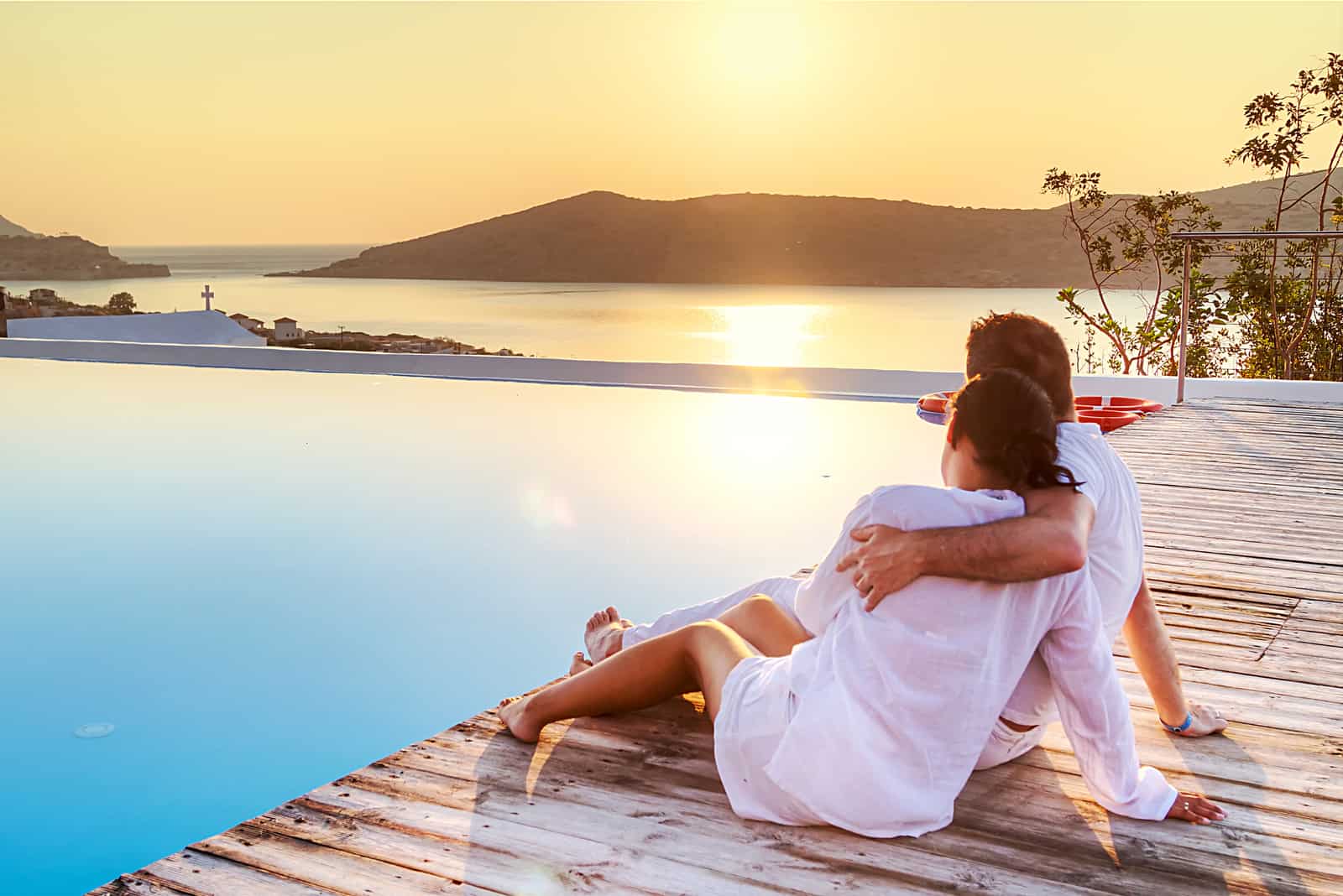 a man and a woman sit on the pier embracing