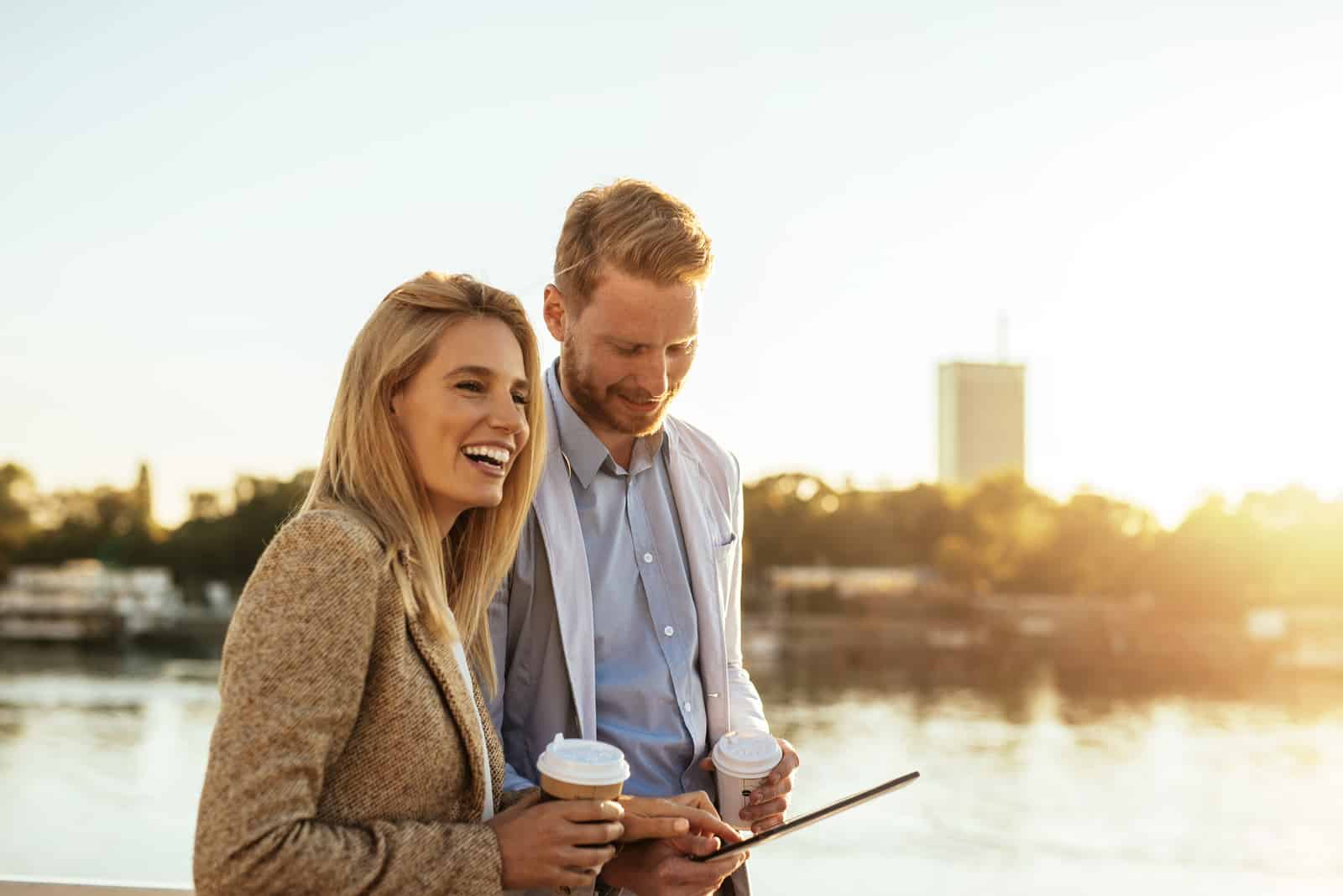 a man and a woman standing holding coffee in their hands