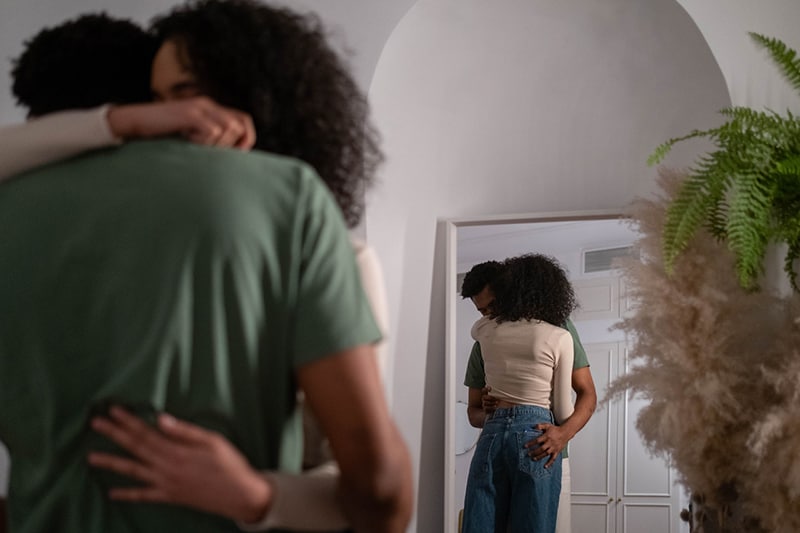 a man and woman hugging while standing in the room