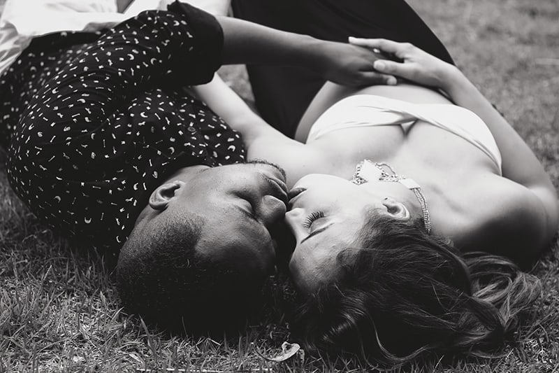 un uomo e una donna che si baciano mentre sono sdraiati a terra
