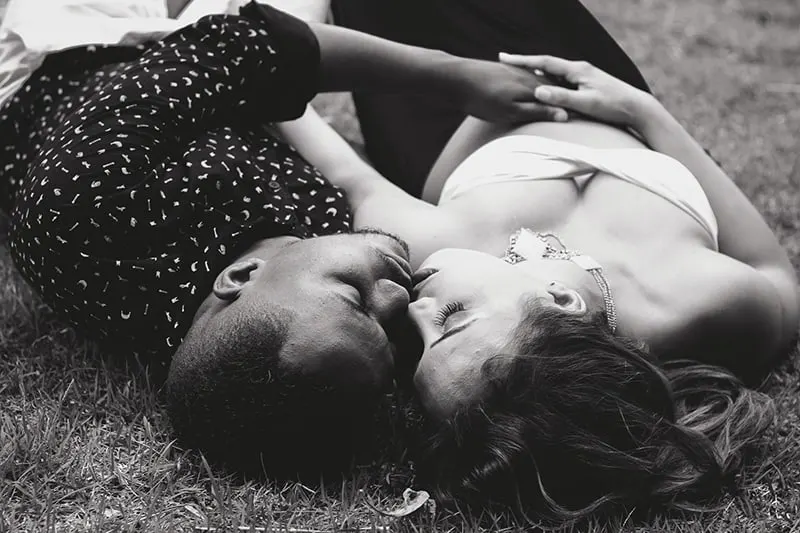 a man and woman kissing while lying on the ground