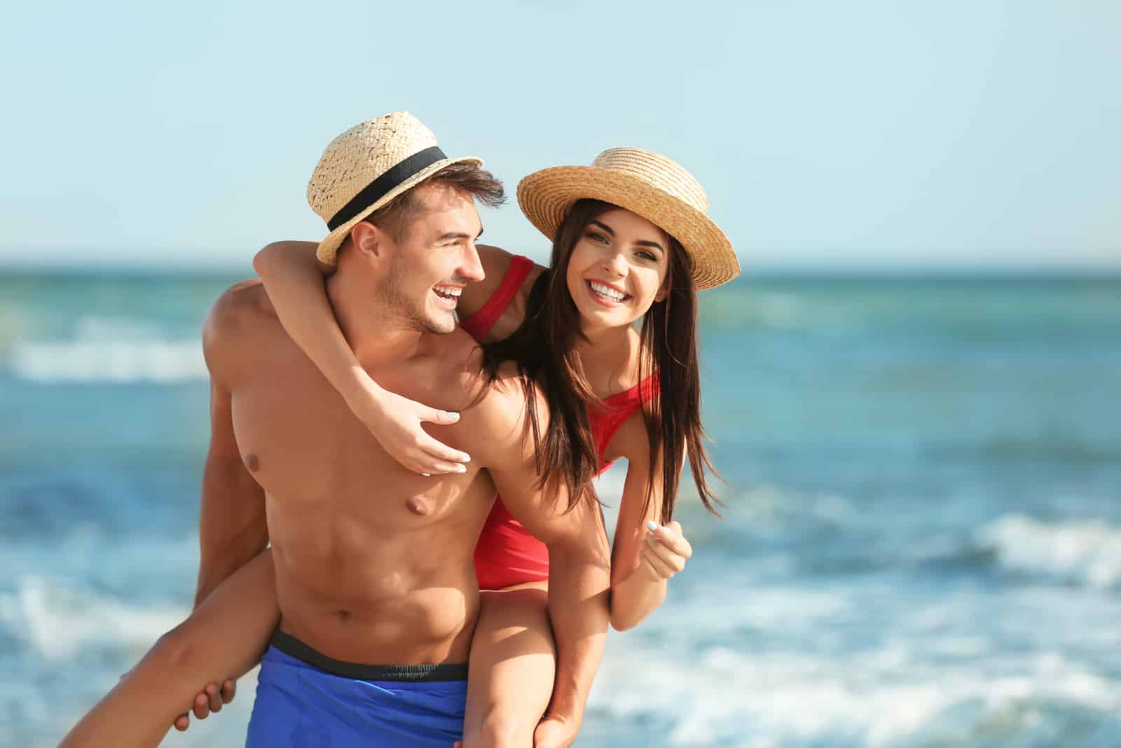 a man carries a woman to the beach and they laugh