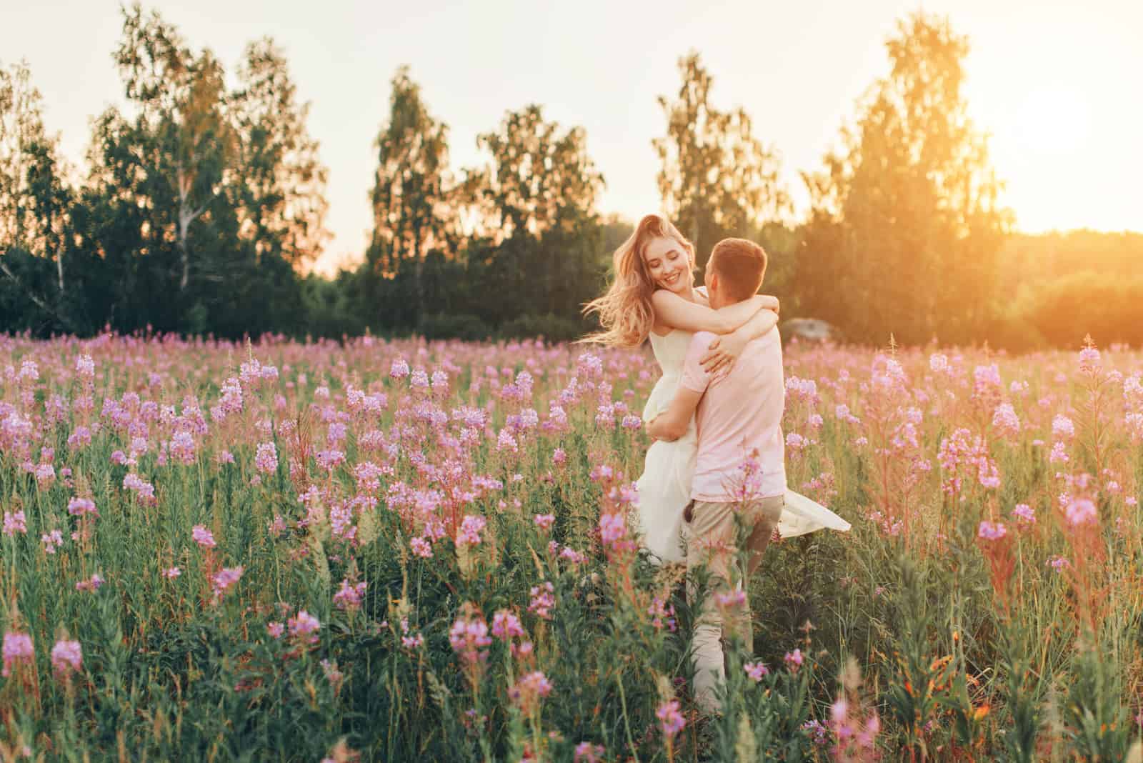 a man hugged a woman in a field of flowers