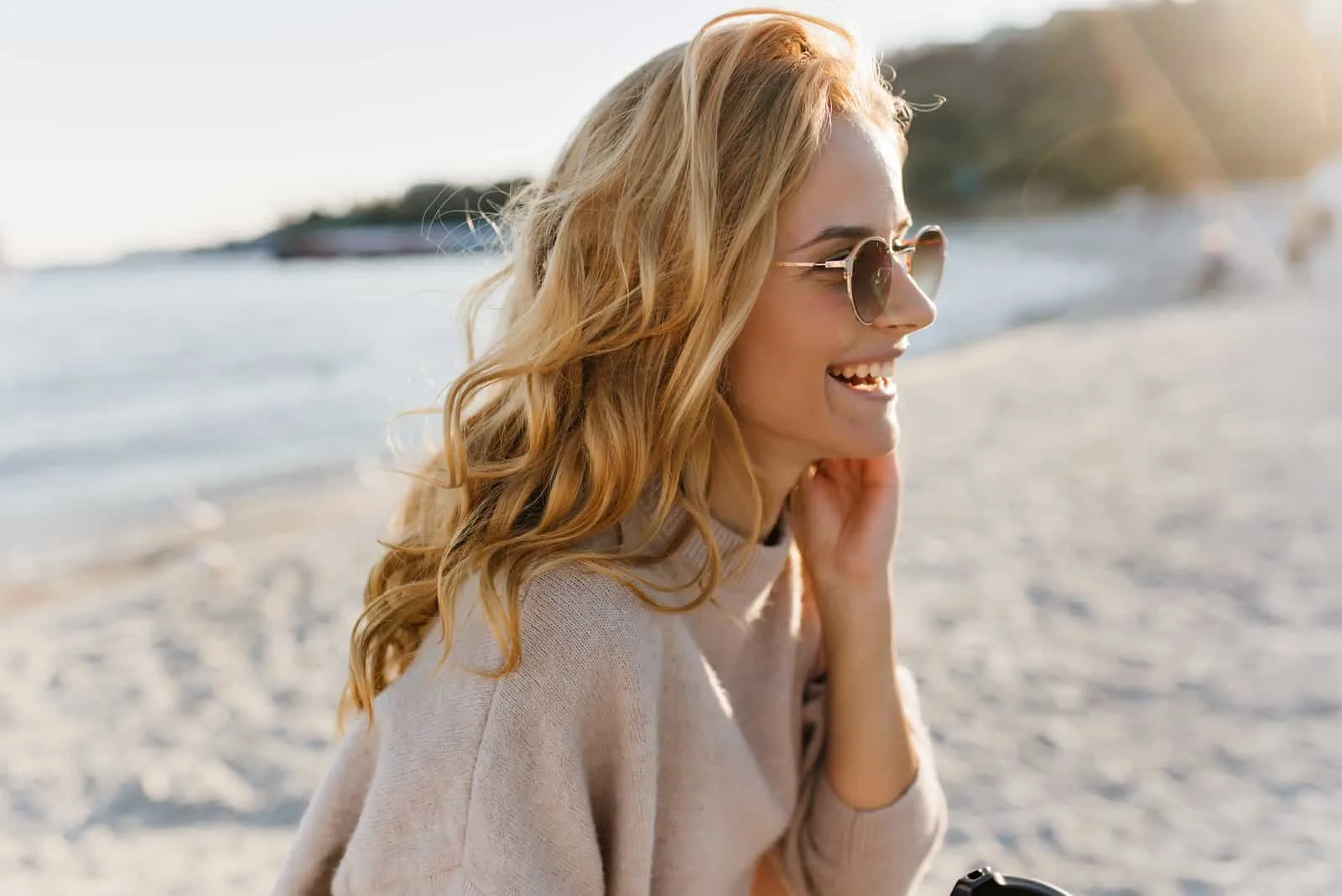 a smiling blonde-haired woman with glasses on her head looks ahead