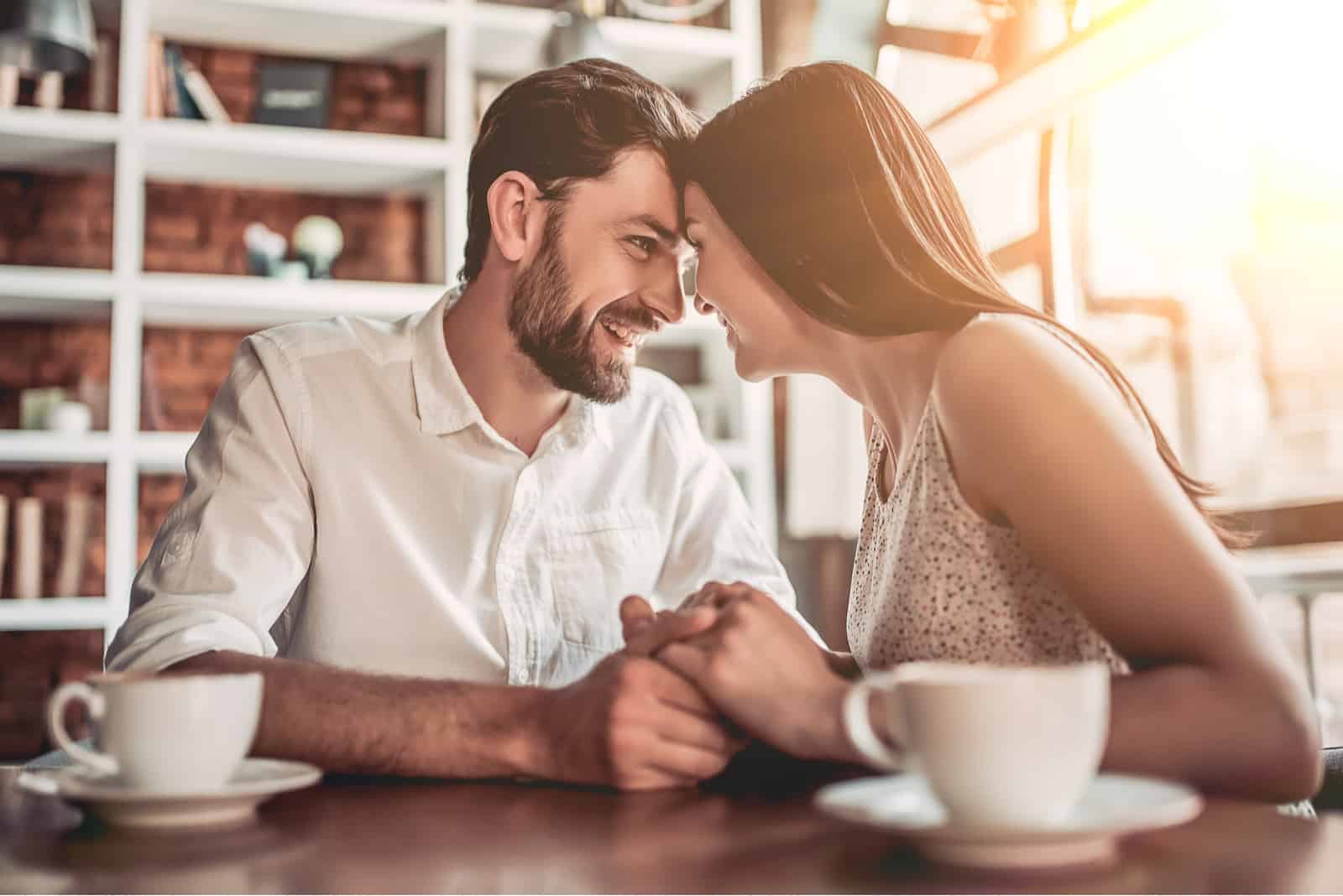 a smiling loving couple cuddles in a cafe