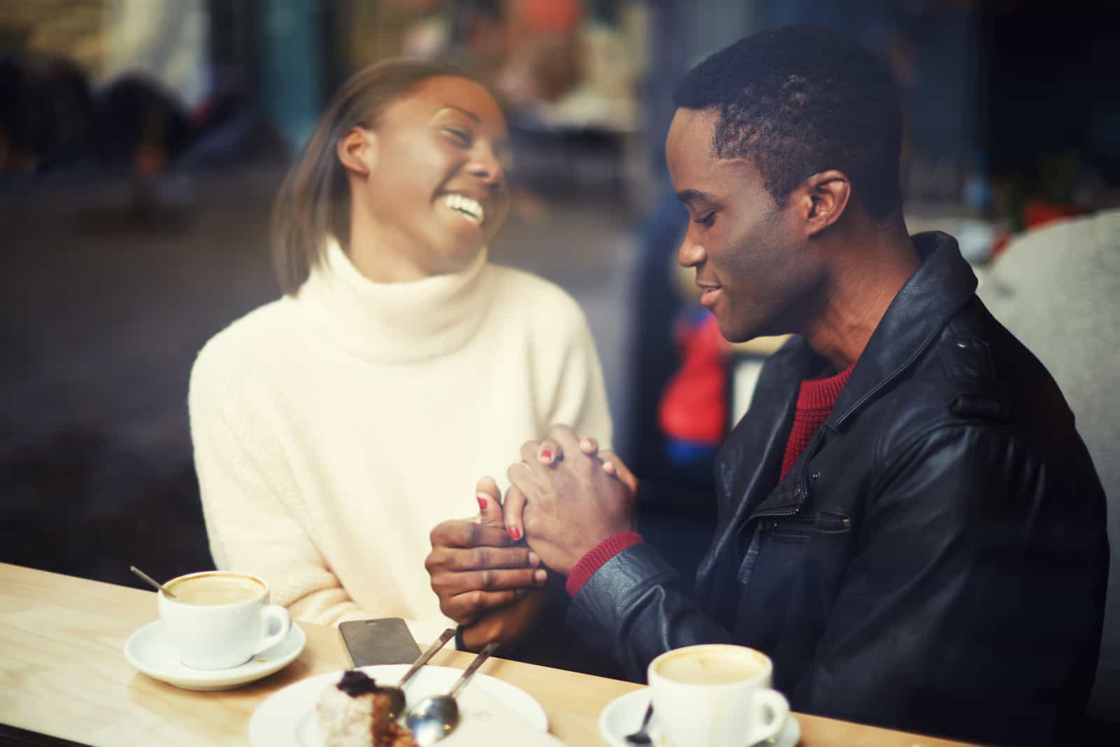 a smiling woman holds the hand of a man as they sit at a table