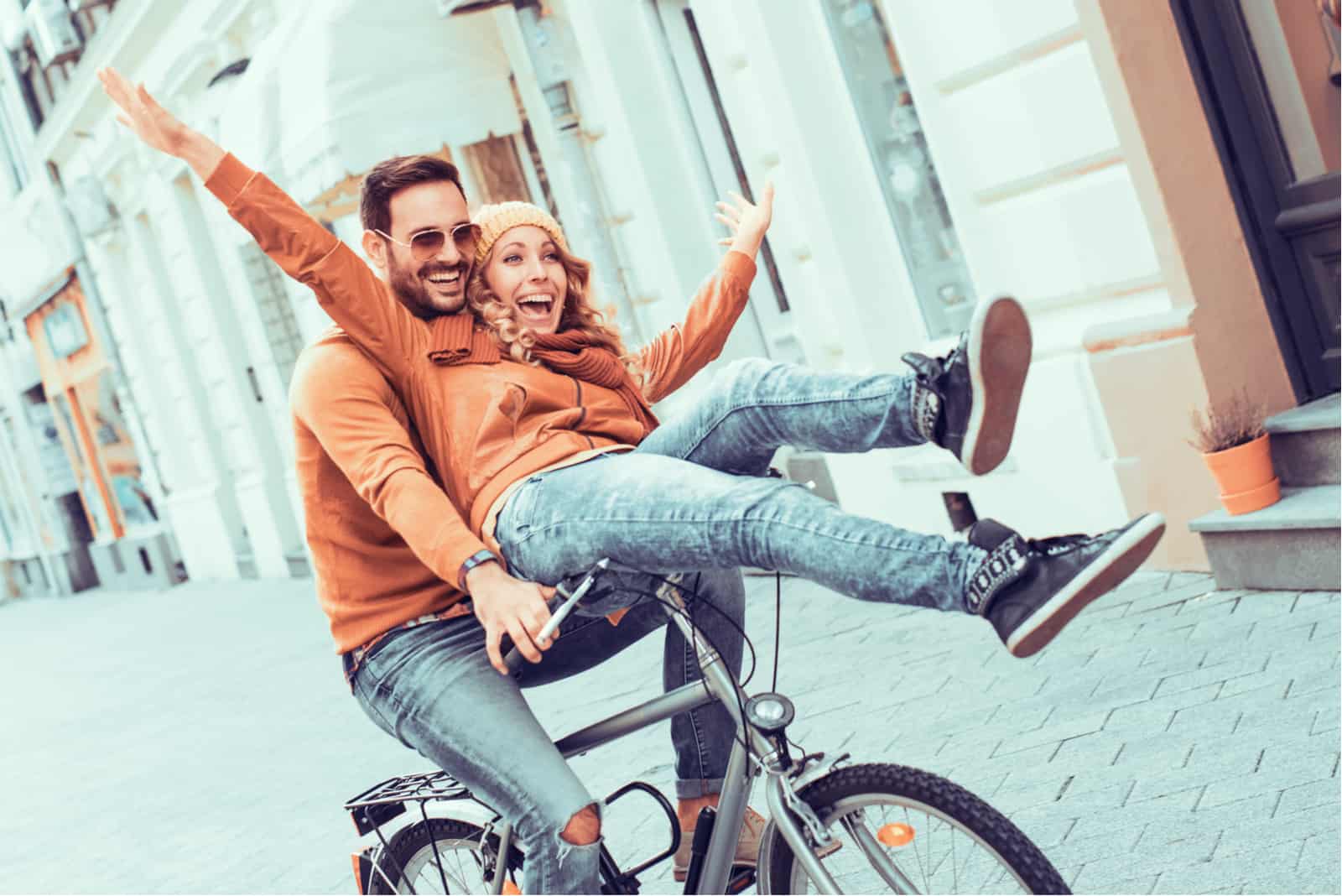 a smiling woman rides a bicycle with a man