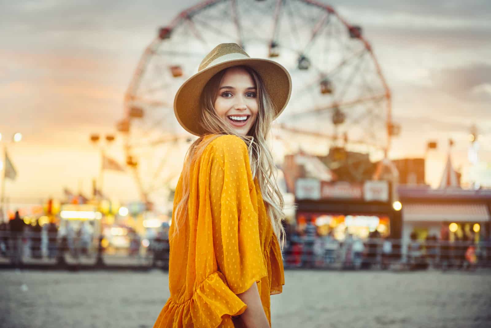 uma mulher sorridente com um chapéu na cabeça está na rua