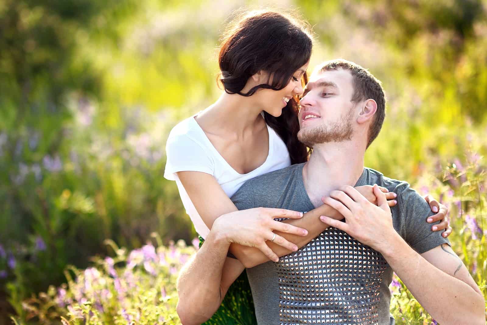 a woman cuddles with a man in a field of flowers