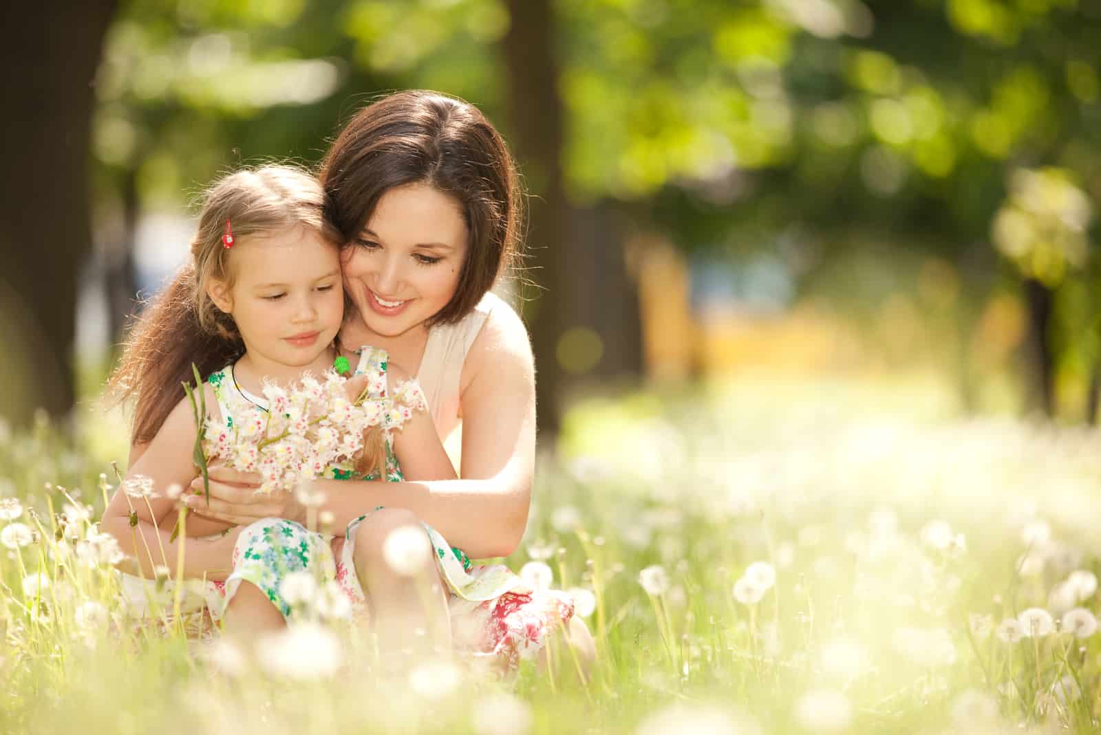 a woman sitting in the grass with a child