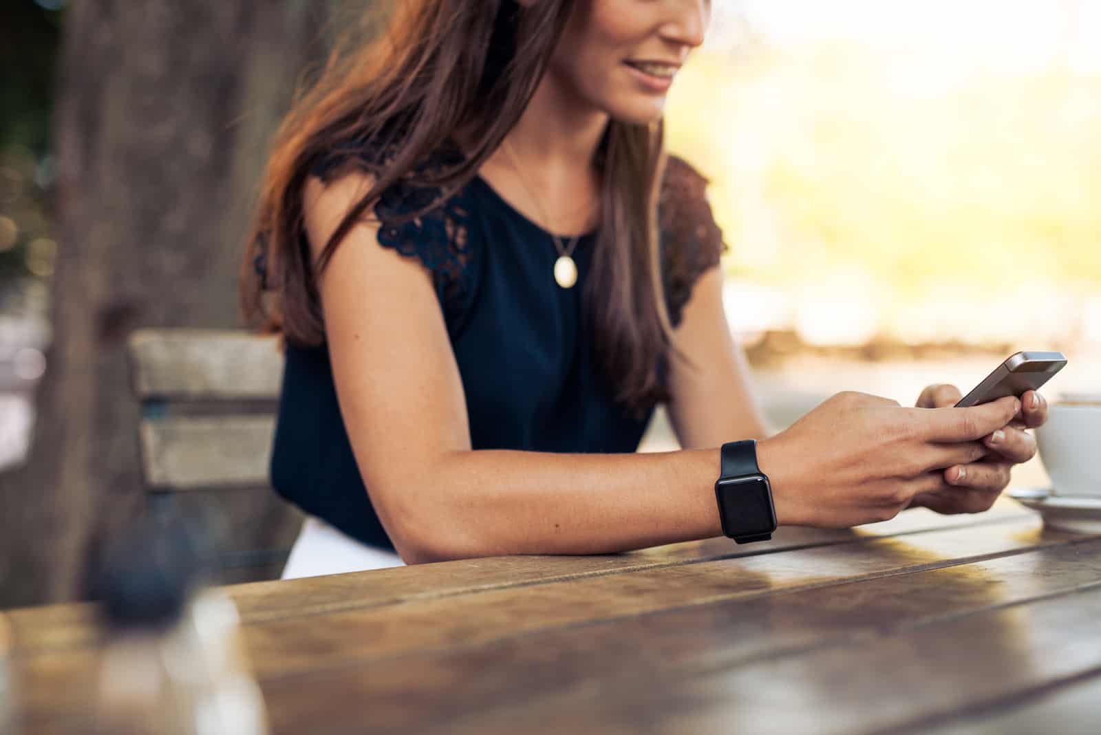 a woman with long black hair sits at a table and buttons on the phone