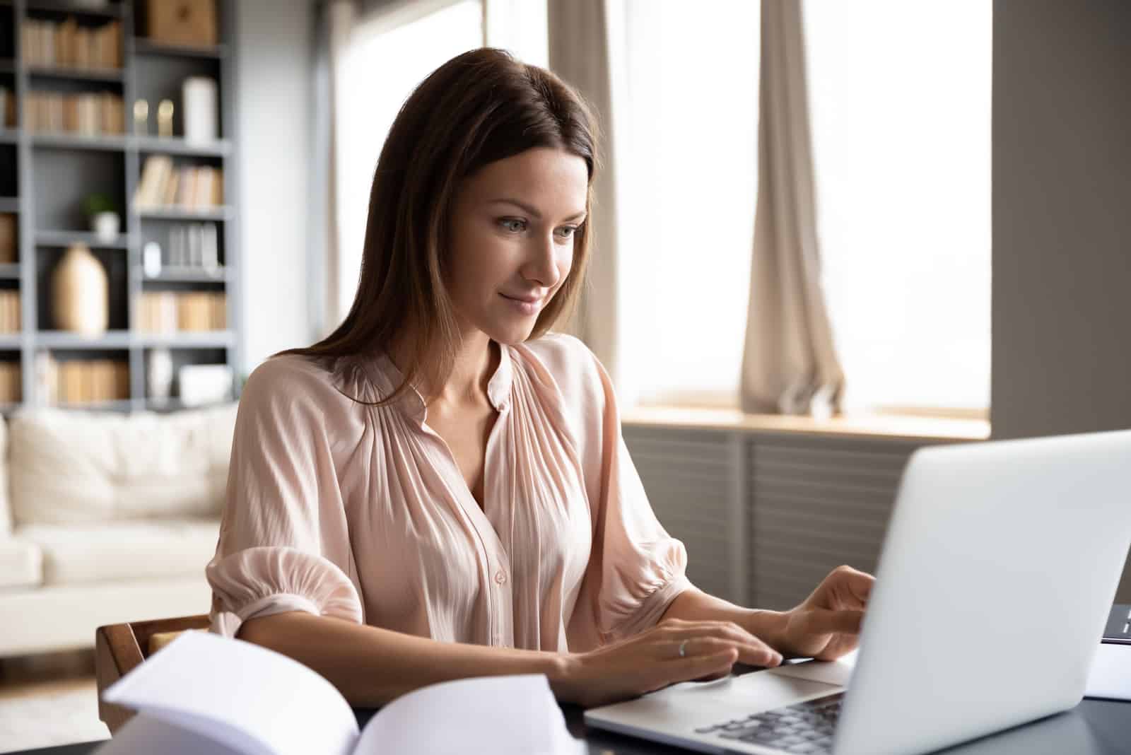 una donna con lunghi capelli neri seduta dietro un computer portatile