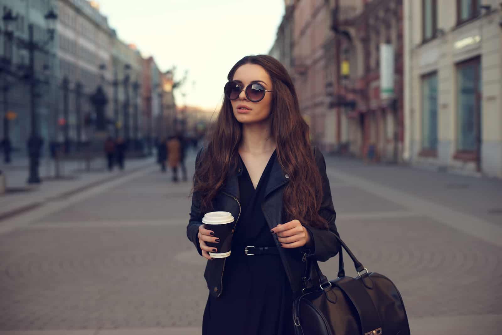 a woman with long black hair walks down the street
