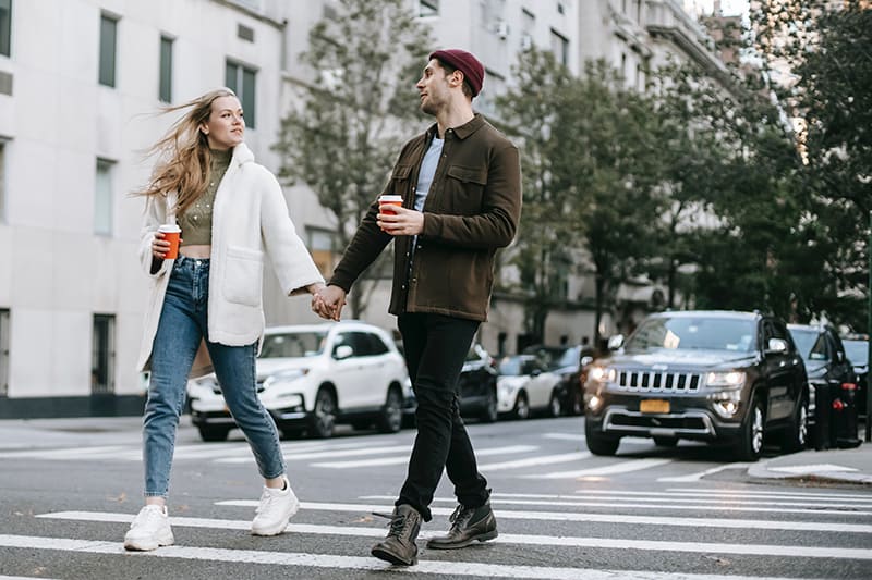 couple holding hands while crossing the street