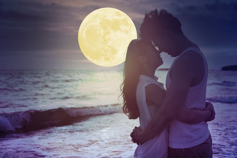 couple hugging on the beach under moonlight