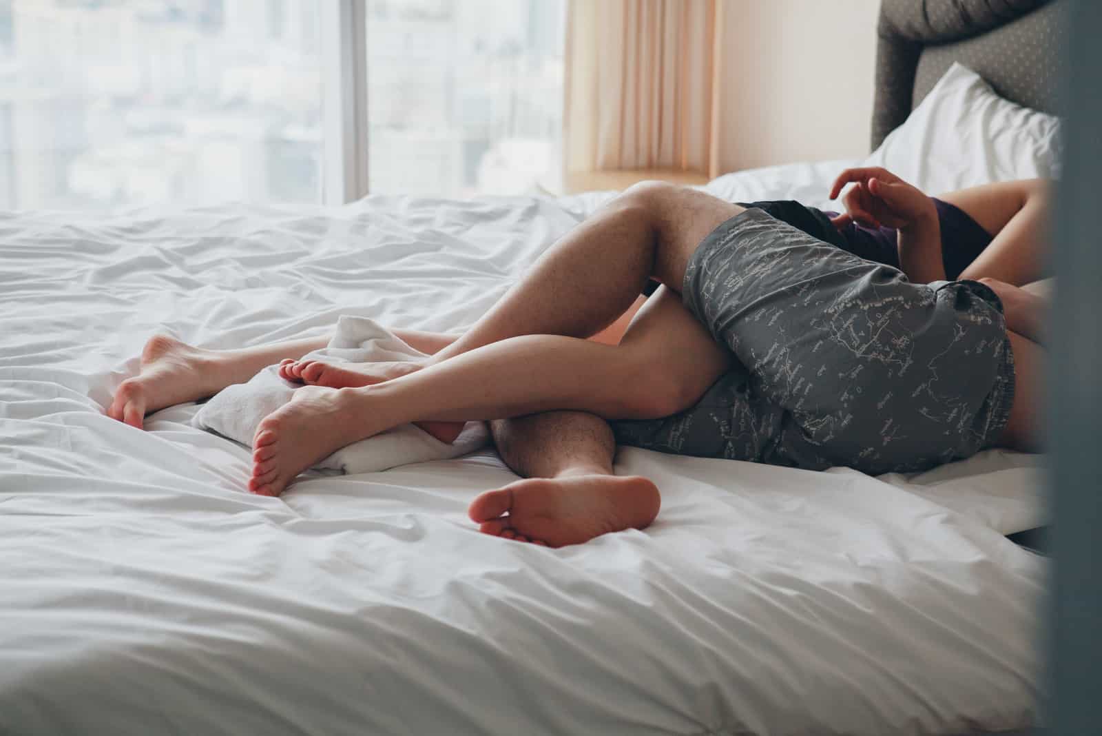 Coppia innamorata sdraiata a letto in hotel