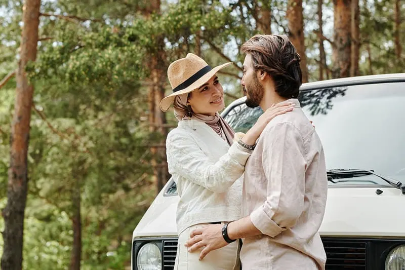 couple looking at each other while standing near the car