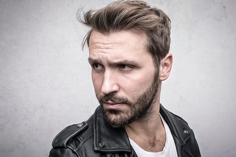 handsome bearded man in leather jacket looking aside