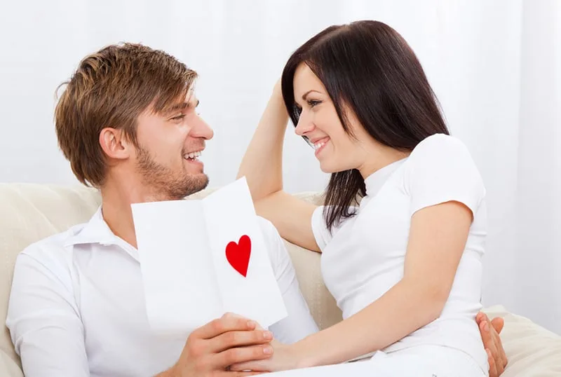happy couple looking at each other holding greeting card