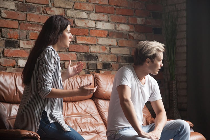 jealous woman arguing with boyfriend while sitting on the couch