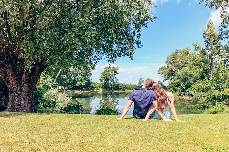 loving couple sitting on the grass in front of lake