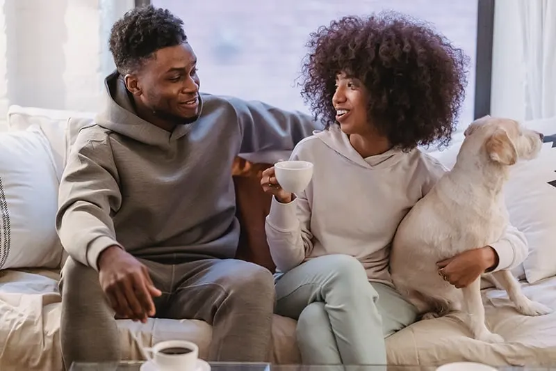 man and woman hanging out sitting on the couch and drinking coffee