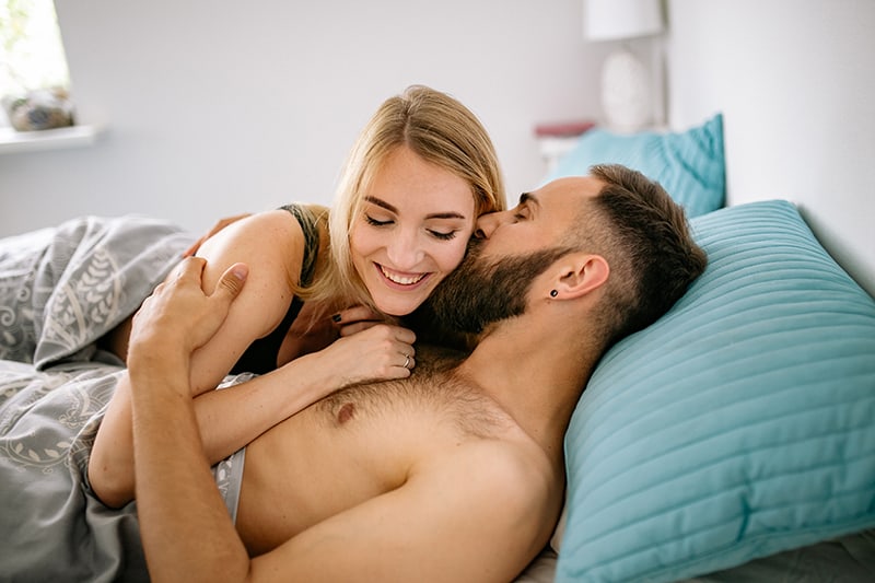 man and woman lying in the bed and cuddling