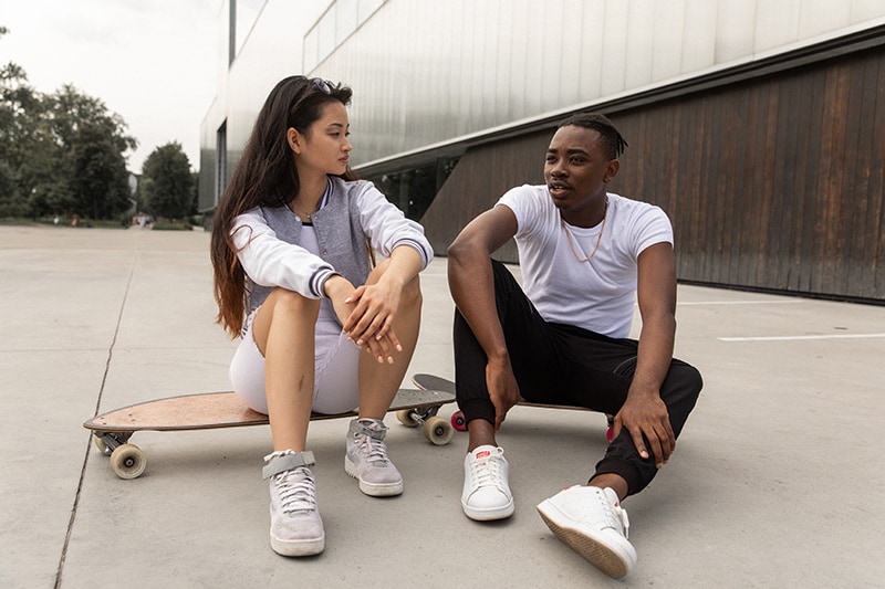 homem e mulher a conversar enquanto descansam nos skates depois de um treino