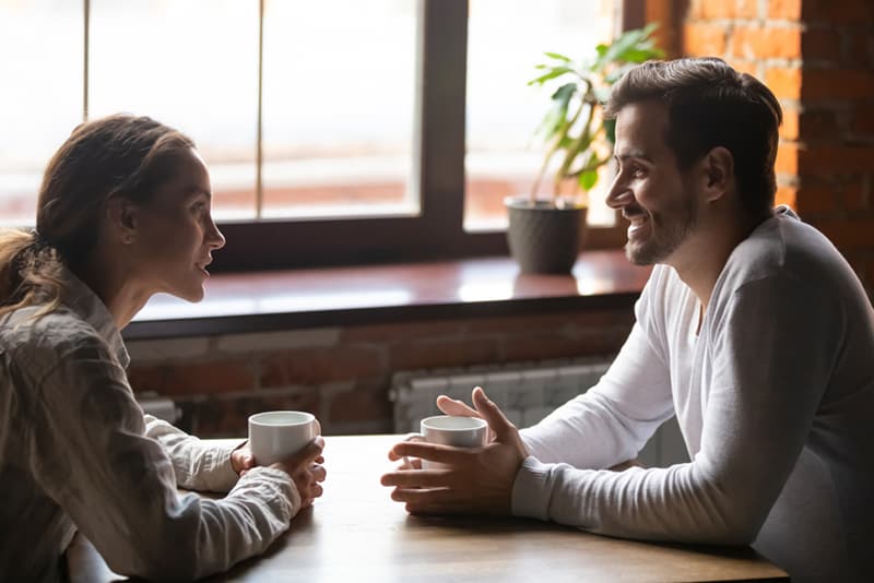 man and woman talking on a date and drinking coffee