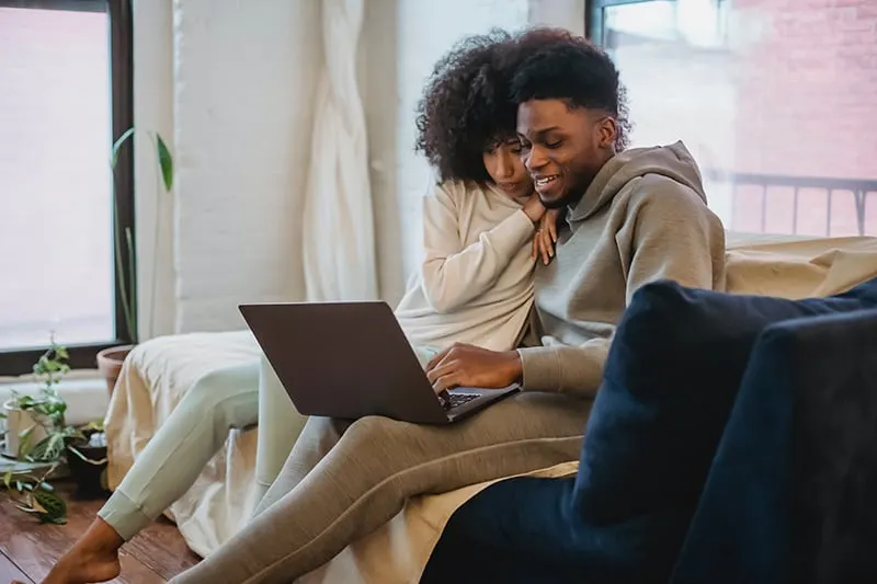 man and woman using laptop while sitting on the couch