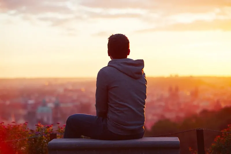 man looking at sunrise sitting on the bench