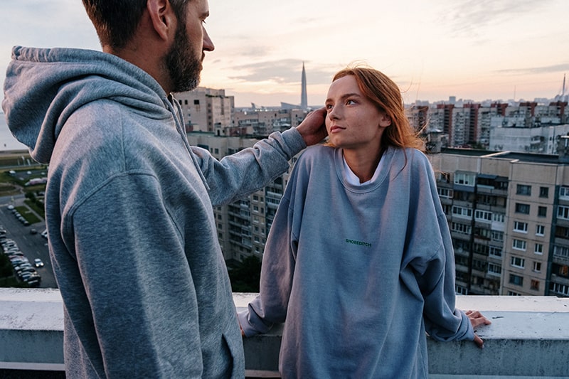 man touching hair of his girlfriend while standing together on the rooftop