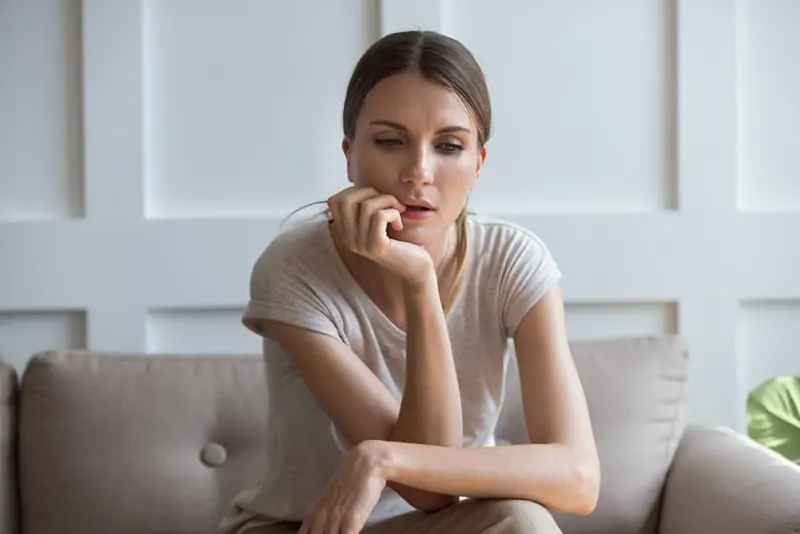 pensive woman sitting on the couch and looking at floor