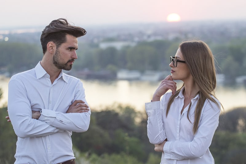 serious man and woman looking at each other while standing outdoors