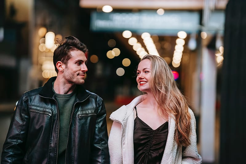 smiling couple looking at each other while walking in the city