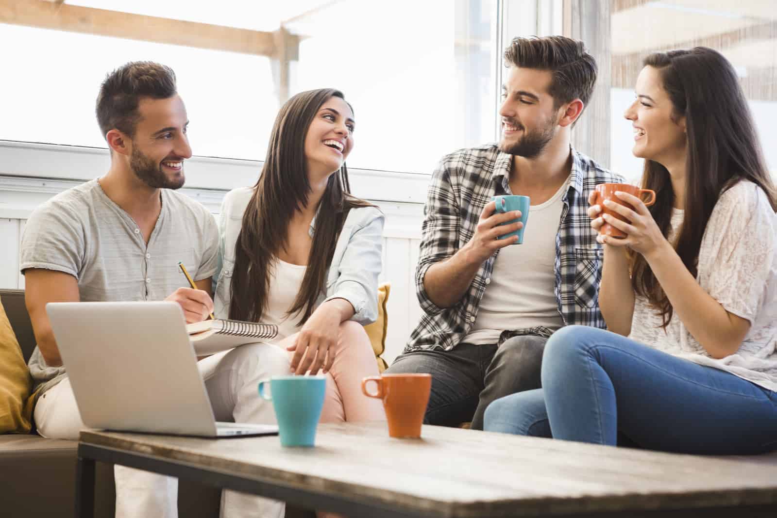 amici sorridenti siedono in casa e parlano